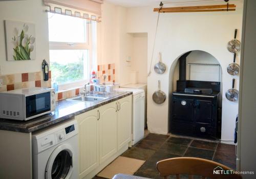a kitchen with a sink and a washing machine at Stone Hall Mill Cottage - Tranquil Countryside Haven in Pembrokeshire in Saint Lawrence