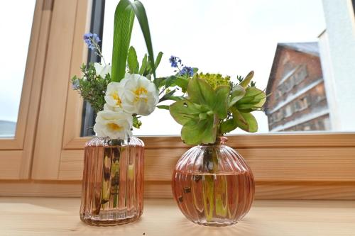 two vases with flowers in them sitting on a window sill at Ferienhof Landerleben in Egg