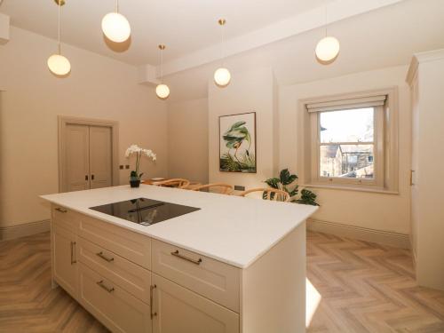 a kitchen with a white island and a table at Chatsworth Suite in Buxton
