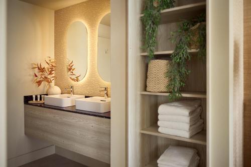 a bathroom with two sinks and a mirror and towels at Van der Valk Palace Hotel Noordwijk in Noordwijk aan Zee