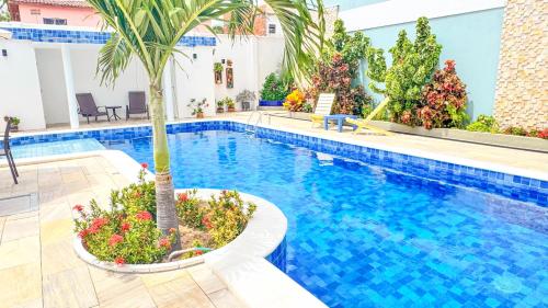 a pool with a palm tree next to a building at Pousada Diane in Trairi