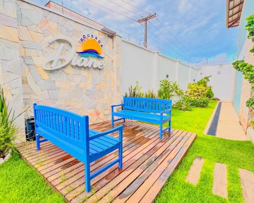 two blue benches sitting on a deck in front of a wall at Pousada Diane in Trairi