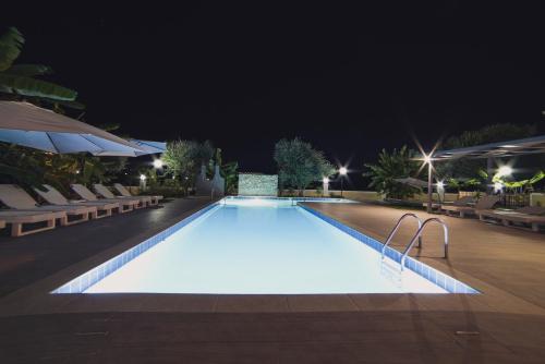 a swimming pool at night with chairs and umbrellas at Mirsini Studios & Apartments in Laganas