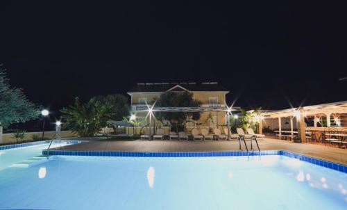 a large swimming pool in front of a building at night at Mirsini Studios & Apartments in Laganas