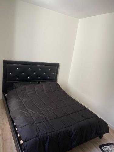 - un lit noir dans un coin de chambre dans l'établissement Appartement, à Saint-Étienne