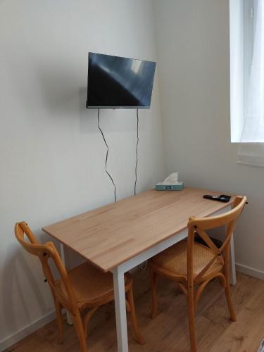 une table en bois avec deux chaises et une télévision murale dans l'établissement Agréable studio -1 personne, à Dijon