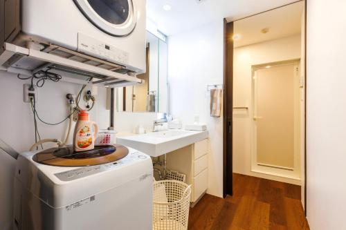 a laundry room with a sink and a washing machine at 恩納村 5部屋 4シャワー 3トイレ 和室 BBQ 居酒屋 コンビニ近く Nakadomari Hills in Onna
