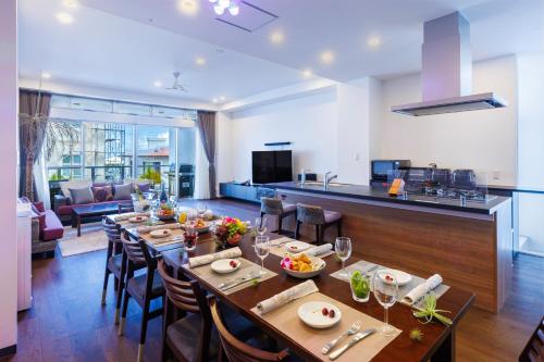 a dining room with a long table and a kitchen at 恩納村 5部屋 4シャワー 3トイレ 和室 BBQ 居酒屋 コンビニ近く Nakadomari Hills in Onna