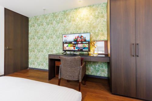 a bedroom with a desk with a television on it at 恩納村 5部屋 4シャワー 3トイレ 和室 BBQ 居酒屋 コンビニ近く Nakadomari Hills in Onna