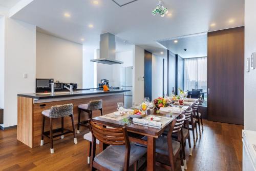 a dining room and kitchen with a long table and chairs at 恩納村 5部屋 4シャワー 3トイレ 和室 BBQ 居酒屋 コンビニ近く Nakadomari Hills in Onna