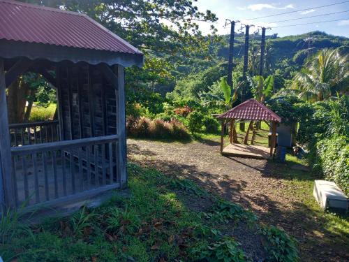 a small house with a gate and a gazebo at BIENVENUE AU SOLEIL LEVANT assier entrée morne savon ,le lorrain in Le Lorrain
