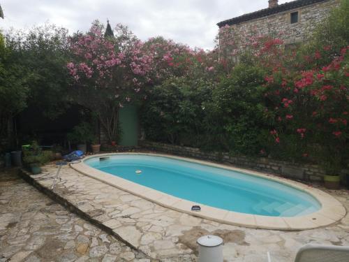 une piscine dans un jardin avec des fleurs roses dans l'établissement Chambre indépendante avec salle de bains et cuisine, à Aubussargues