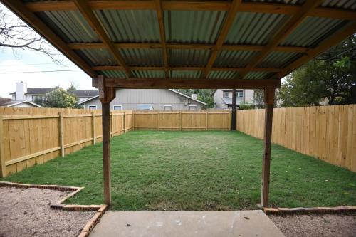 a large backyard with a wooden fence and a pergola at Stylish 2 suite condo minutes to food, music, fun in Austin