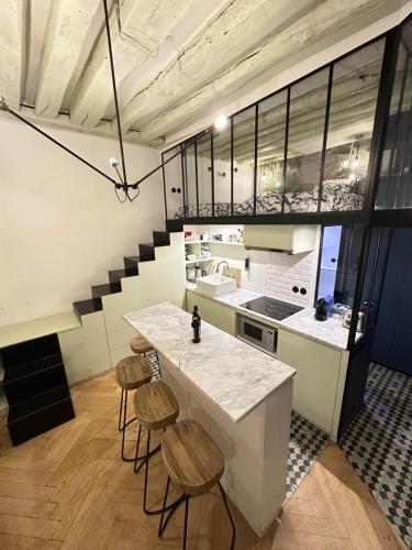 une cuisine avec un comptoir et des tabourets dans une pièce dans l'établissement Cosy Flat In Marais, à Paris