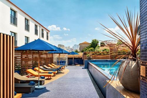 a pool with lounge chairs and umbrellas on a building at Forte de Gaia, Autograph Collection in Vila Nova de Gaia