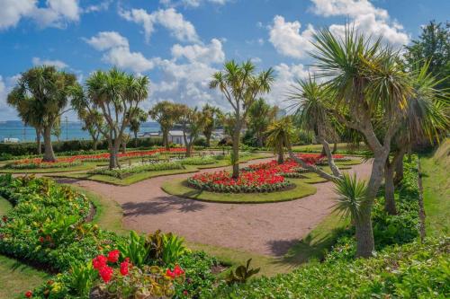 a garden with red flowers and palm trees at Luxury Holiday Apartments in Torquay