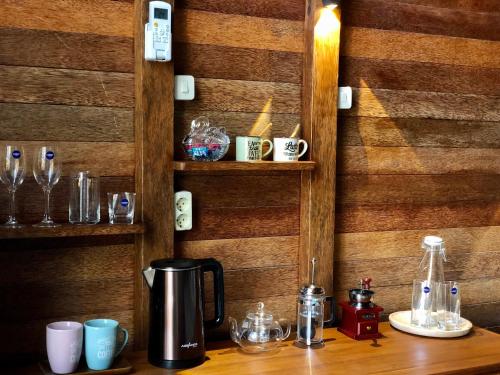 a coffee maker on a wooden table with cups and glasses at Lagoon Bungalows Bali in Nusa Dua
