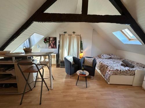 - une chambre mansardée avec un lit et une table dans l'établissement Studio Sur les Toits - Centre Historique, à Quimper