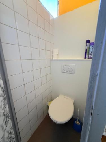 a bathroom with a toilet with a white tiled wall at gites de Warincthun in Audinghen