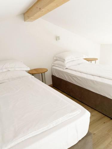 two beds in a room with white walls and wooden floors at Lagom Home Vipavski Križ in Ajdovščina