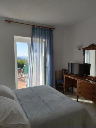 a bedroom with a bed and a desk and a window at Hotel Villa al Mare in Ischia