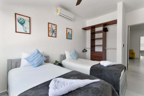 two beds in a bedroom with white walls and blue pillows at Perfect resort style House in Playa del Carmen