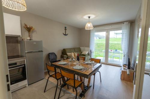 une cuisine avec une table avec des chaises et un réfrigérateur dans l'établissement 3 04 appartement avec jardin et parking privé, à Pinchefalise