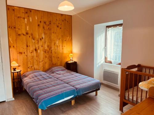 une chambre avec un lit et un mur en bois dans l'établissement La grange de Pierrot proche de Salers, 10pers, 4ch, à Girgols