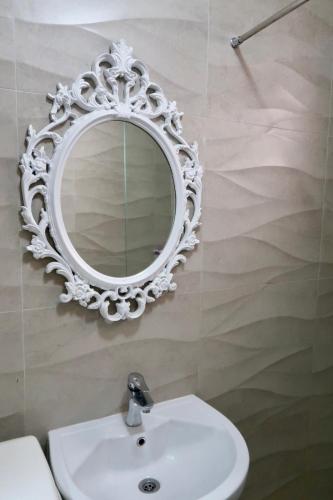 ein Badezimmer mit Waschbecken und Spiegel an der Wand in der Unterkunft Green Apartment in Pristina