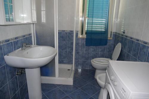 baño de azulejos azules con lavabo y aseo en Parco Meridiana, en Scalea