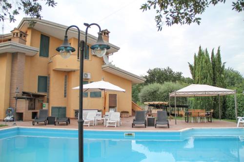 a pool with chairs and umbrellas next to a house at Boteroom Relais in La Volla