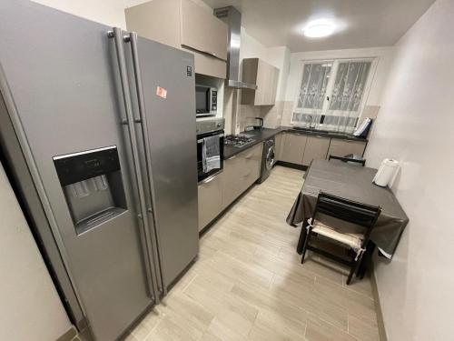 une cuisine avec un réfrigérateur en acier inoxydable et une table dans l'établissement TM Style appartement, à Villejuif