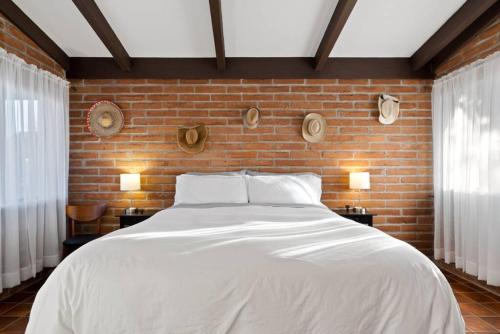 une chambre avec un lit blanc et un mur de briques dans l'établissement Spacious casita with desert and mountain views, à Tucson