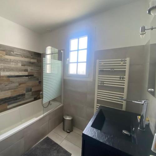 La salle de bains est pourvue d'un lavabo, d'une baignoire et d'une fenêtre. dans l'établissement Le Bananier, à Les Sables-dʼOlonne