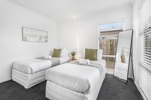 a white room with two beds and a mirror at Central 2brm Retreat, Modern, Close to Shopping - By KOSH BNB in Hamilton