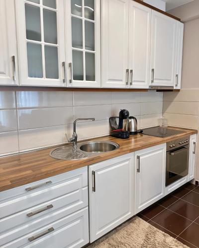 Una cocina con gabinetes blancos y un fregadero. en The Modern Flat, en Pristina