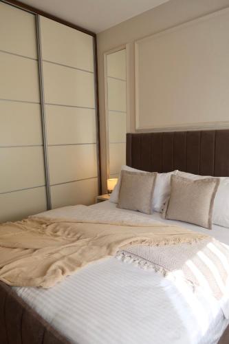 una cama grande con sábanas y almohadas blancas en The Modern Flat, en Pristina