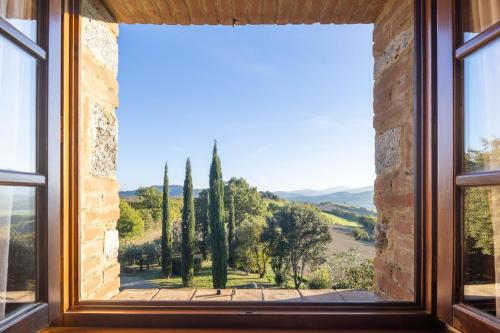 a window with a view of trees and mountains at Casale la Peschiera by VacaVilla in Monteguidi