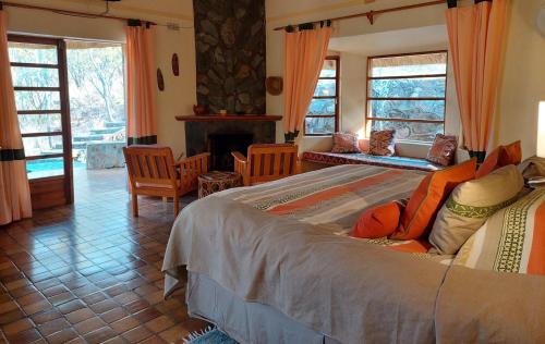 a bedroom with a large bed and a fireplace at Musangano Lodge in Odzi