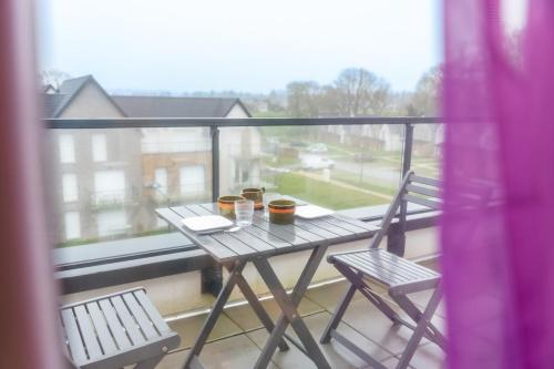 une table et des chaises sur un balcon avec une fenêtre dans l'établissement Cocon de la Baie, terrasse et parking privé, à Saint-Valery-sur-Somme