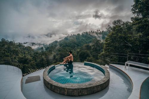 a man sitting in a swimming pool in the mountains at Mountain Floating Cloud in Ban Kai Noi