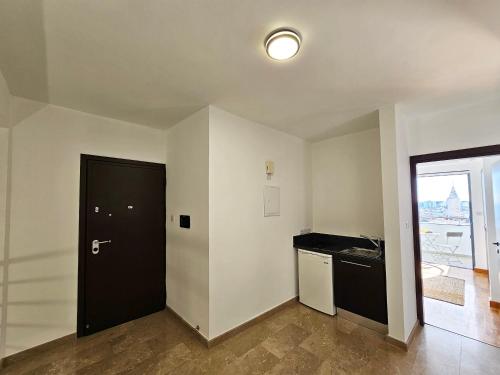 an empty room with a black door and a kitchen at Dios Ponte Finikoudes Beachfront in Larnaka