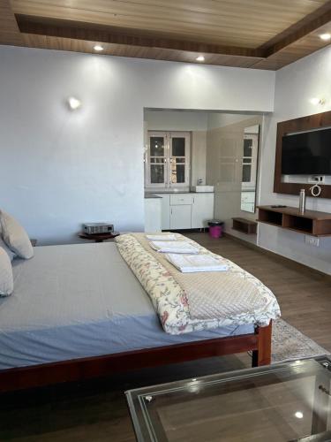 a bedroom with a large bed and a kitchen at The Whitegrove Retreat in Mukteswar