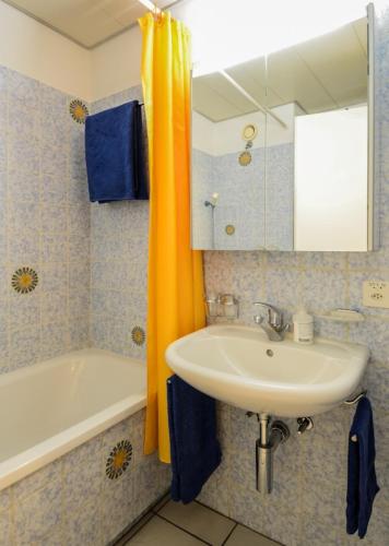 a bathroom with a sink and a tub and a mirror at Ferienwohnung C07 in Orselina