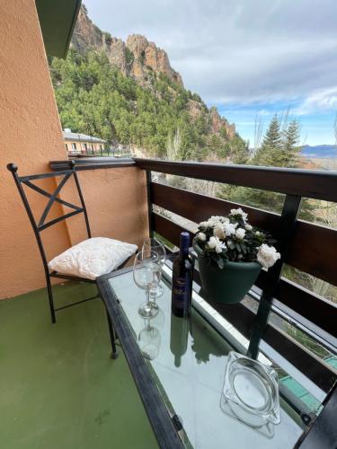 a table with wine glasses and a plant on a balcony at Hotel El Guerra in Güéjar-Sierra