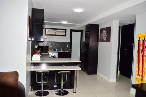 a kitchen with black cabinets and bar stools at City Centre Self-Catering Suites in Windhoek