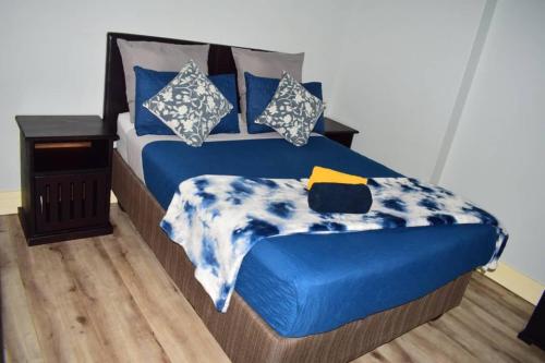a bed with blue and white sheets and pillows at City Centre Self-Catering Suites in Windhoek