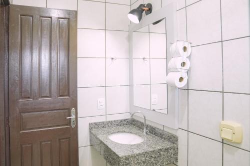 a bathroom with a sink and a mirror and a door at Pousada Schmitz in Florianópolis