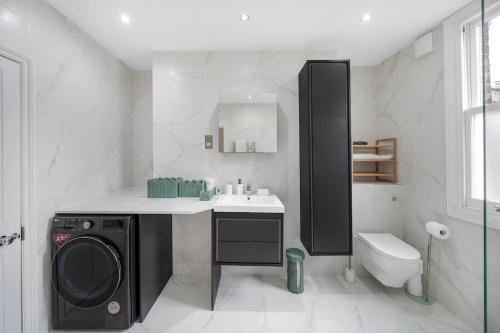 a bathroom with a washing machine and a sink at New stylish 3-Bed Pimlico House near Big Ben in London