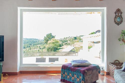 a large window in a living room with a ottoman at Window to the Valley in Santo Isidoro